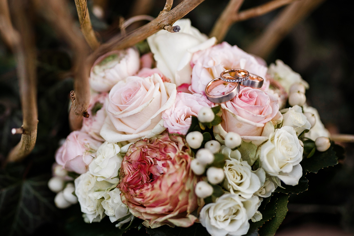 Idee Hochzeitsfoto Eheringe rosegold und platin gebürstet ohne Stein und Verlobungsring rosegold mit Steinen auf Brautstrauß Winter aus Hochzeitsblumen Winter Rosen in Pastelltönen- Hochzeitsfotografin aus Berlin hat Winterhochzeit am Wasser in Brandenburg im Landgasthof Zum Mühlenteich begleitet © www.hochzeitslicht.de