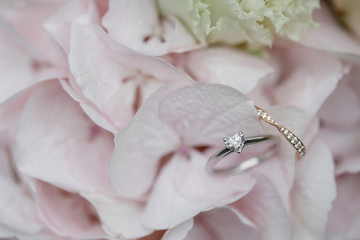 Detailfoto der Tiffany Eheringe mit zartrosa Blumen bei Hochzeit im Patrick Hellmann Schlosshotel Grunewald Berlin © Hochzeit Berlin www.hochzeitslicht.de