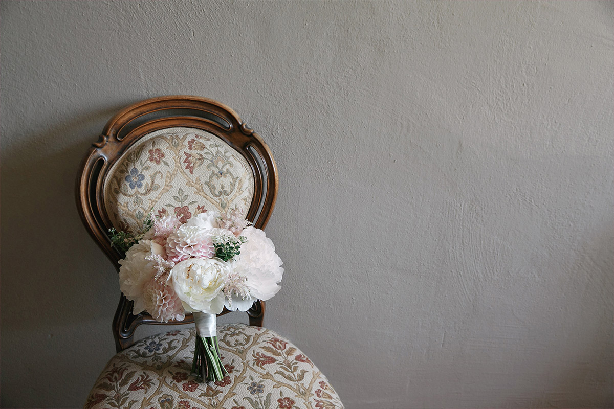 Hochzeitsfoto von Brautstrauß aus Dahlien und Pfingstrosen in Pastellfarben auf Stuhl bei Vintage-Hochzeit im Gut Suckow Brandenburg © Hochzeitsfotograf Berlin www.hochzeitslicht.de