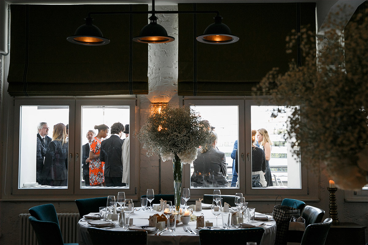 Hochzeitsreportagefoto vom geschmückten Festraum und Gästen auf Terrasse bei stilvoller Soho House Berlin Hochzeit - Soho House Berlin Hochzeitsfotograf © www.hochzeitslicht.de