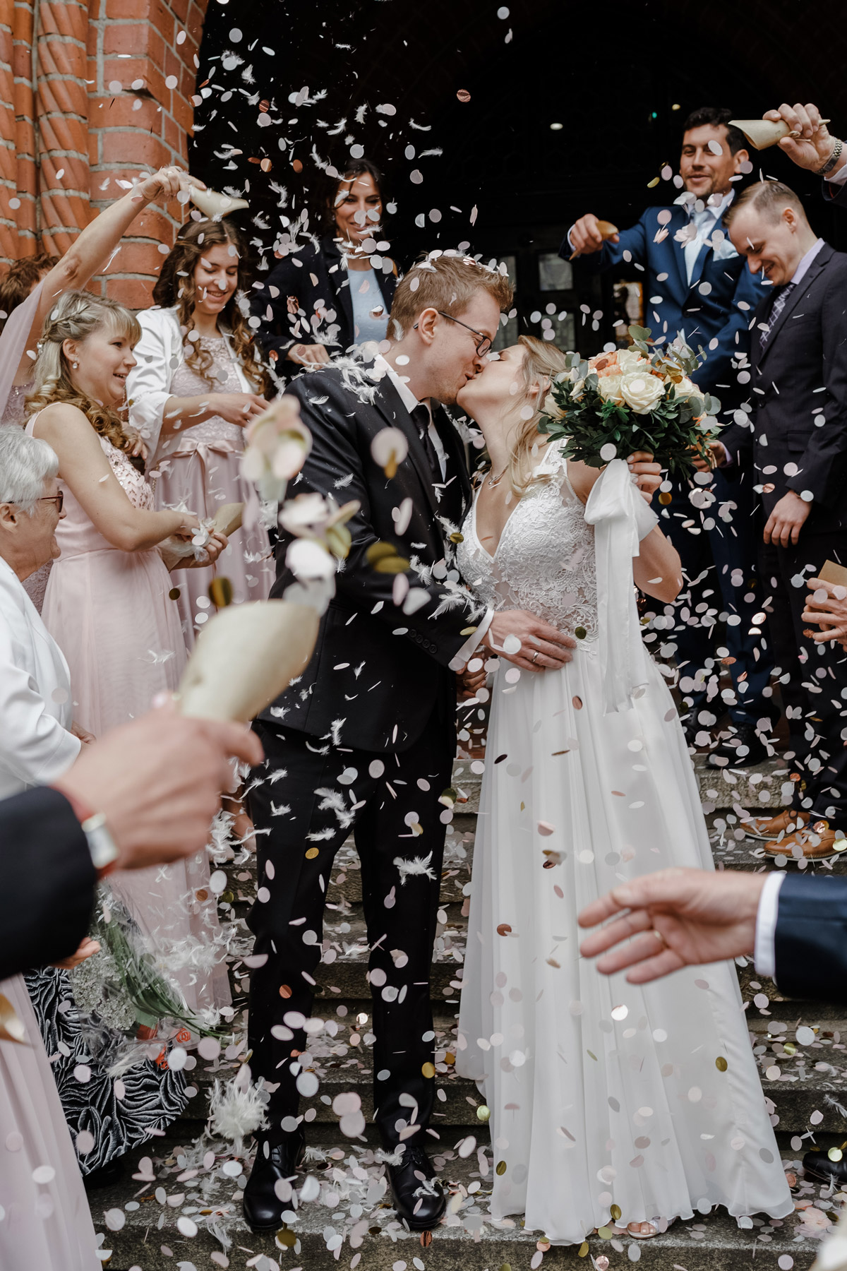 Hochzeitsfoto Brautpaar Hochzeit Standesamt Gratulation mit Konfetti und Federn; Braut in langem Brautkleid mit Spitzenoberteil und ohne Ärmel; Bräutigam in schwarzem Anzug Standesamt - Standesamt Köpenick Hochzeitsfotograf © www.hochzeitslicht.de