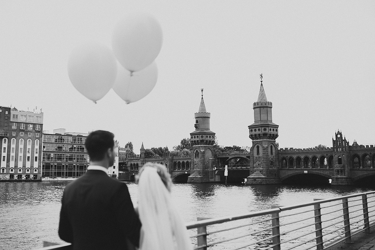 schwarz-weiß Hochzeitsfoto von Brautpaar mit Luftballons an Oberbaumbrücke - Berlin Friedrichshain Hochzeitsfotograf © www.hochzeitslicht.de