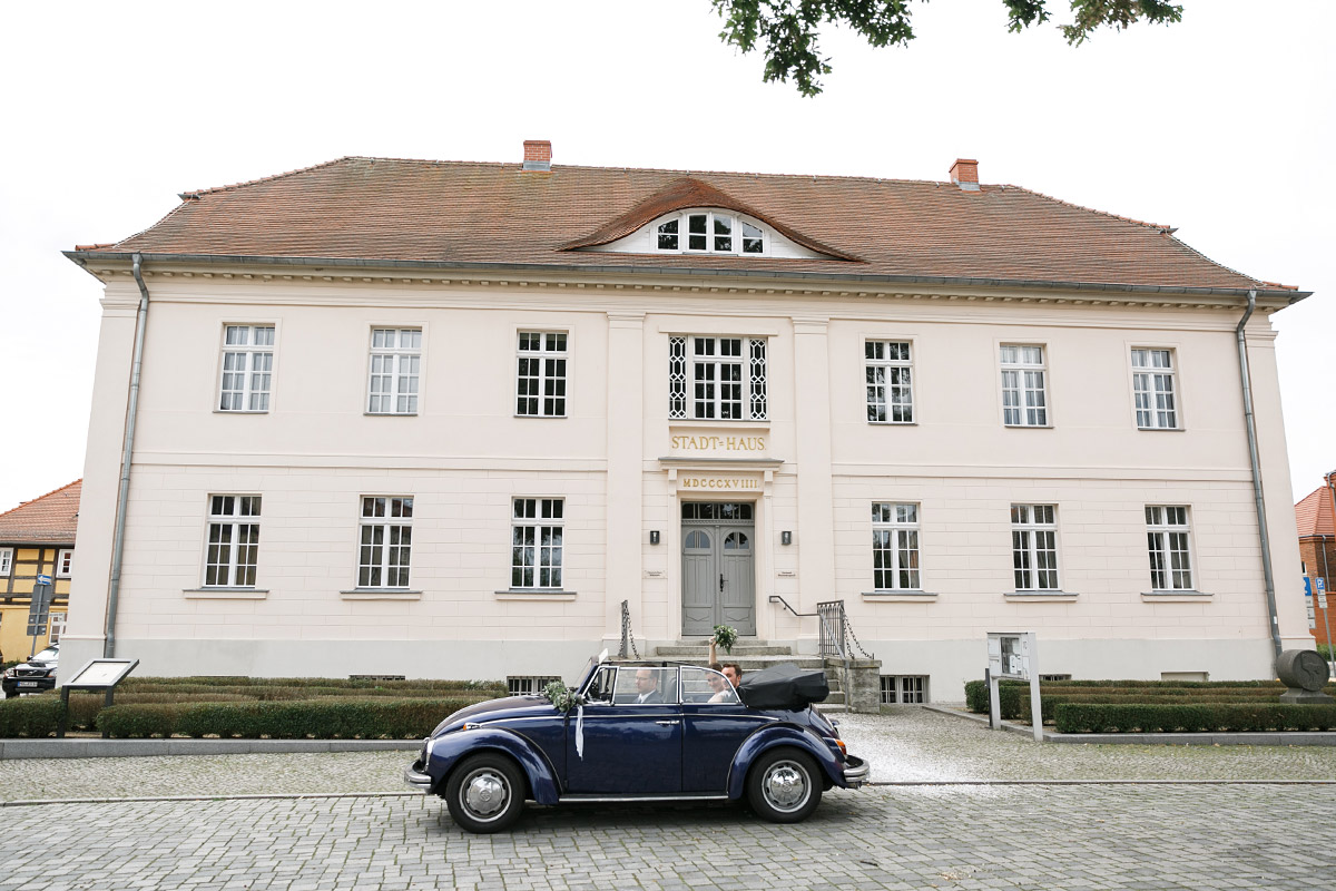 Hochzeitsreportagefoto von Brautpaar in Hochzeitsauto Käfer-Cabrio vor Altem Stadthaus Strausberg - Landhaus Garzau Märkische Schweiz Hochzeitsfotograf © www.hochzeitslicht.de