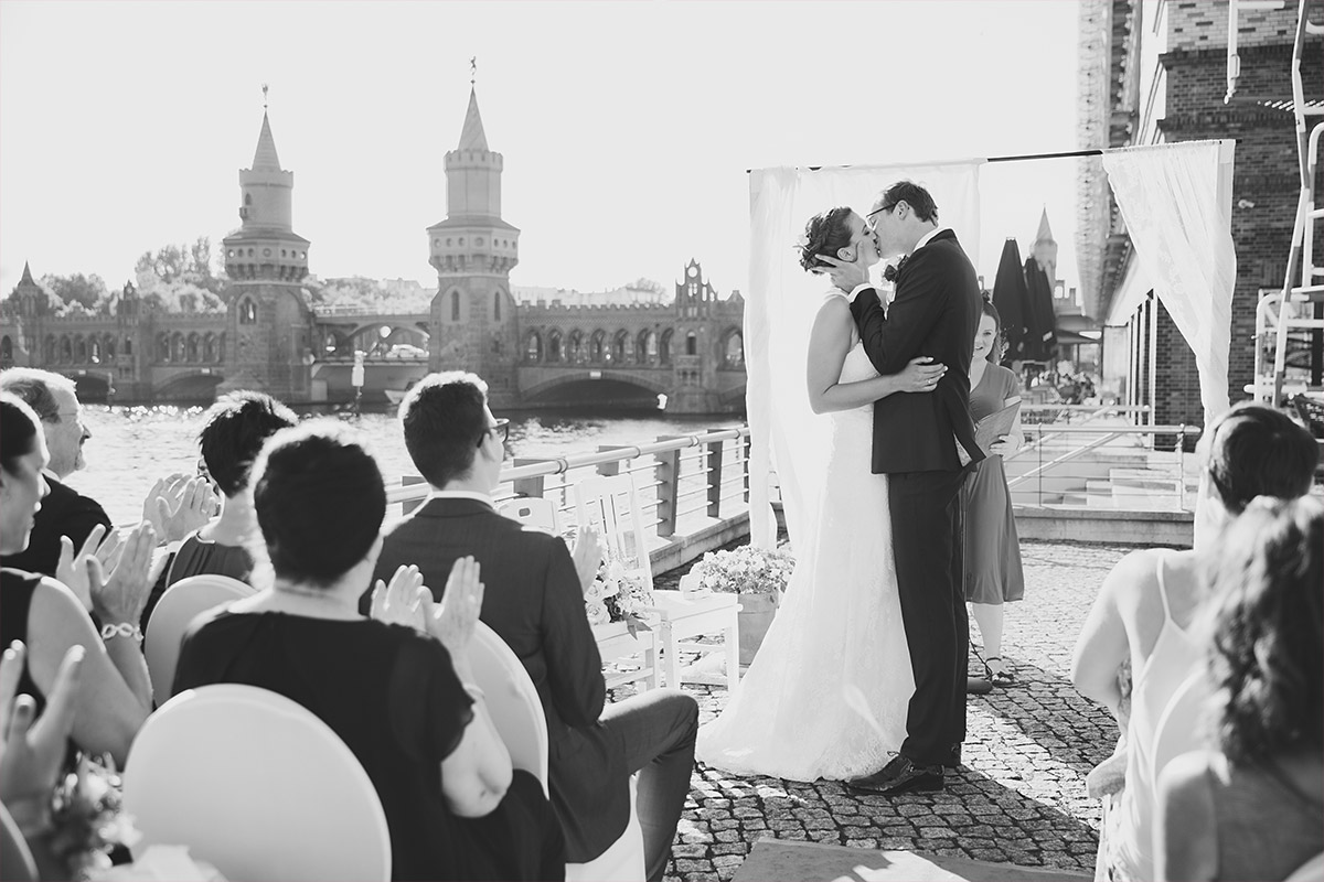 Hochzeitsfoto von Kuss bei Ja-Wort bei freier Trauung an Spree mit Blick auf Oberbaumbrücke - Spreespeicher Hochzeitsfotograf © www.hochzeitslicht.de