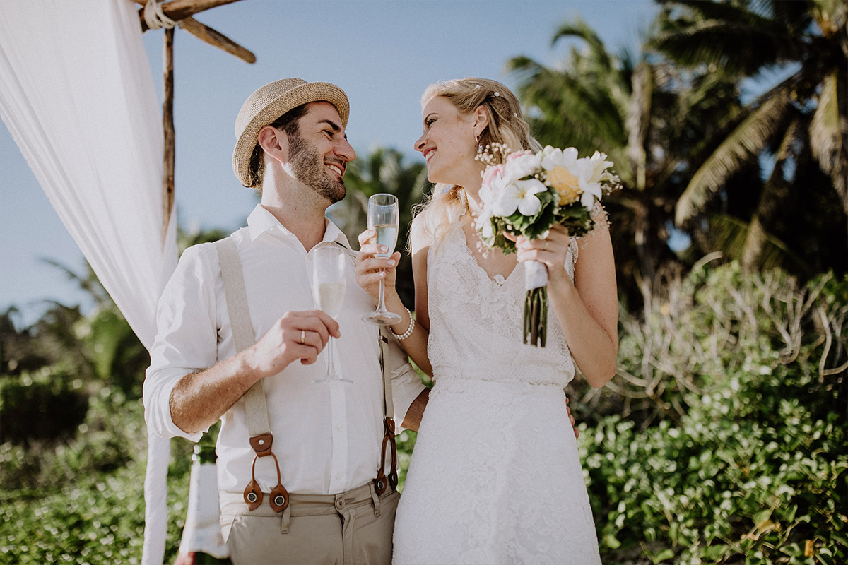 Brautpaar beim Anstoßen nach Trauung am Meer - Strandhochzeit Seychellen Hochzeitsfotograf © www.hochzeitslicht.de