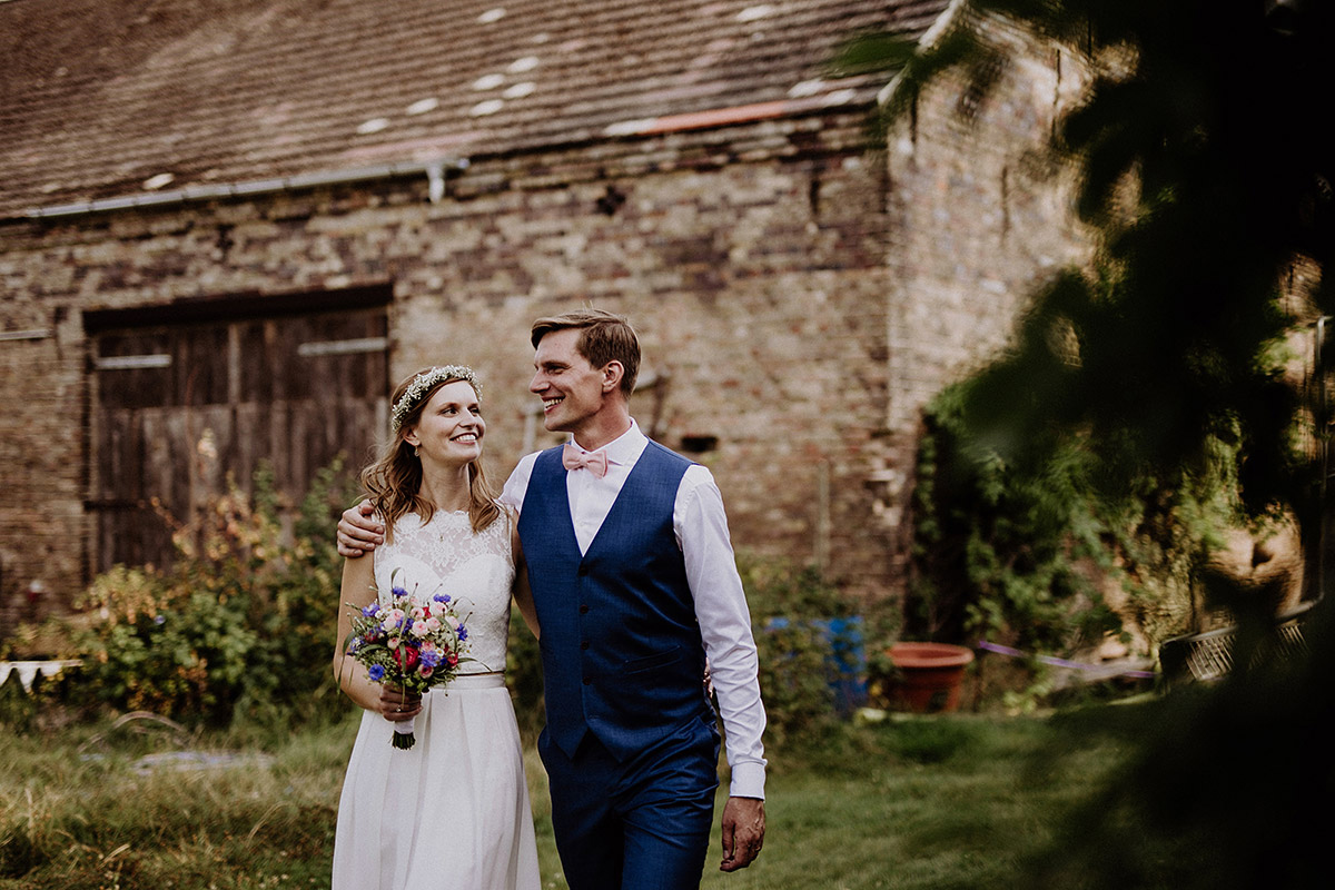 Hochzeitsfoto Brautpaar mit Bräutigam in blauem Anzug und Braut in Zweiteiler Brautkleid - Vierseithofcafé Brandenburg Hochzeitsfotograf © www.hochzeitslicht.de