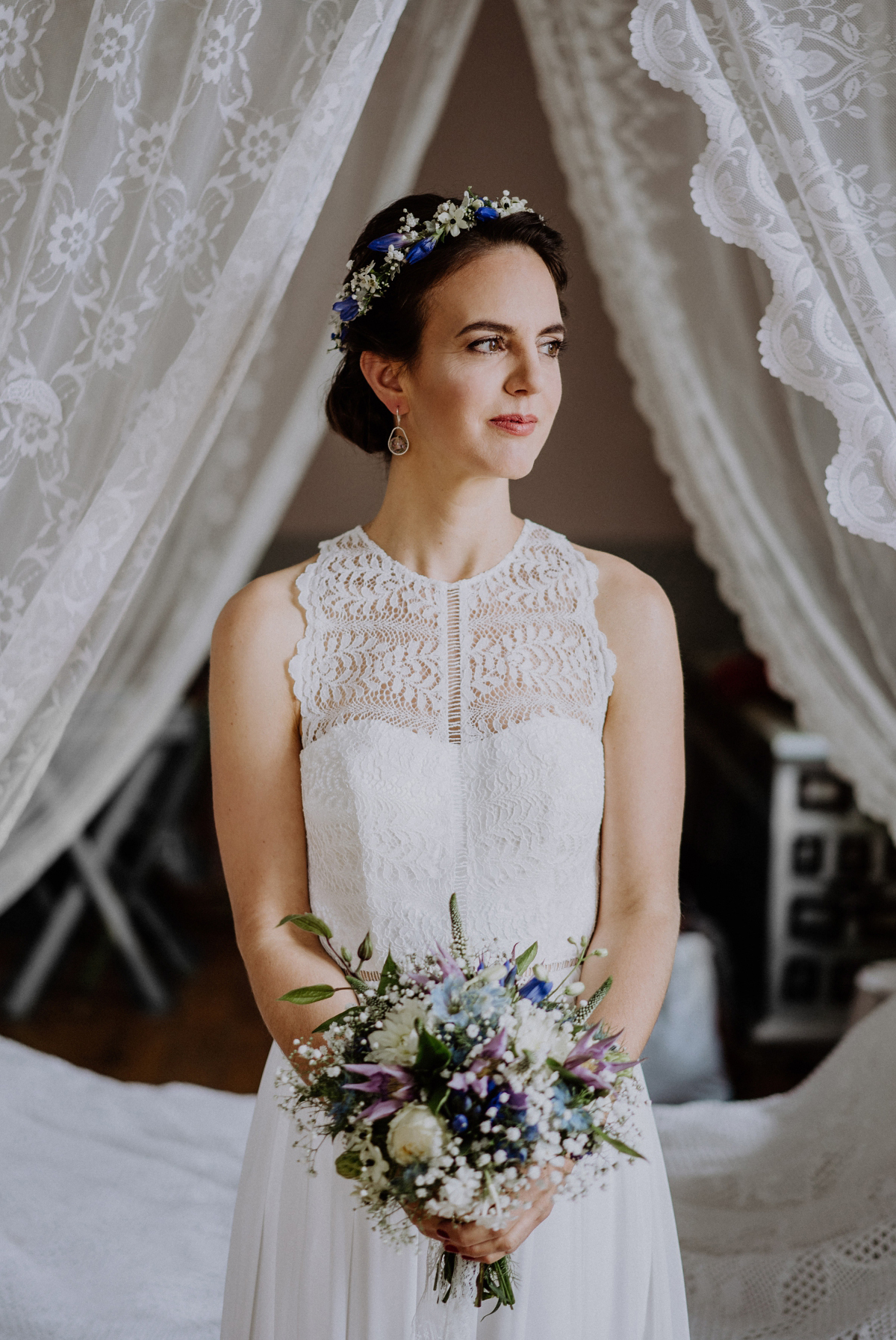 Hochzeitsfoto Braut elegante Landhochzeit; Hochzeitskleid schulterfrei, Oberteil Spitze transparent, tiefer Rücken, langer Tüllrock; Frisur Braut gesteckt Knoten im Nacken mit Haarkranz aus Blumen weiß blau; Brautstrauß Wildblumen blau, weiß, lila; Brautohrringe schlicht- Boho-Scheunenhochzeit in Brandenburg im Schmetterlingsgarten mit Hochzeitsfotografin aus Berlin © www.hochzeitslicht.de