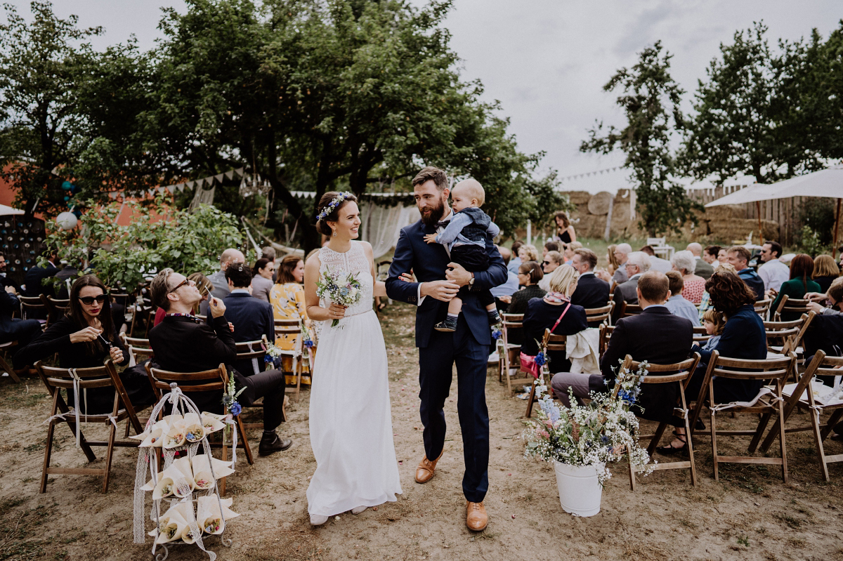 Hochzeitsfoto Auszug Braut mit Kind freie Trauung draußen im Garten bei Landhochzeit - Boho-Scheunenhochzeit in Brandenburg im Schmetterlingsgarten mit Hochzeitsfotografin aus Berlin © www.hochzeitslicht.de