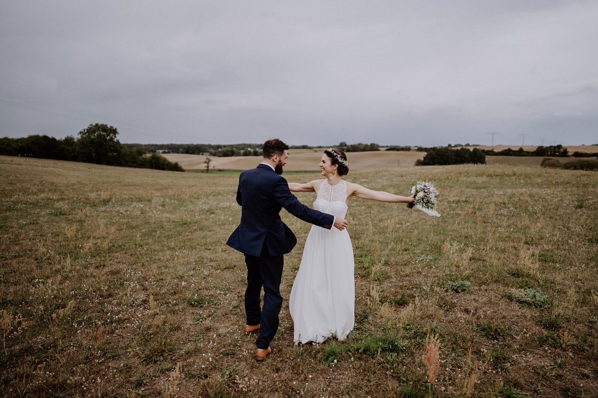 Hochzeitsfoto tanzendes Brautpaar Feld Regenhochzeit - Boho-Scheunenhochzeit in Brandenburg im Schmetterlingsgarten mit Hochzeitsfotografin aus Berlin © www.hochzeitslicht.de