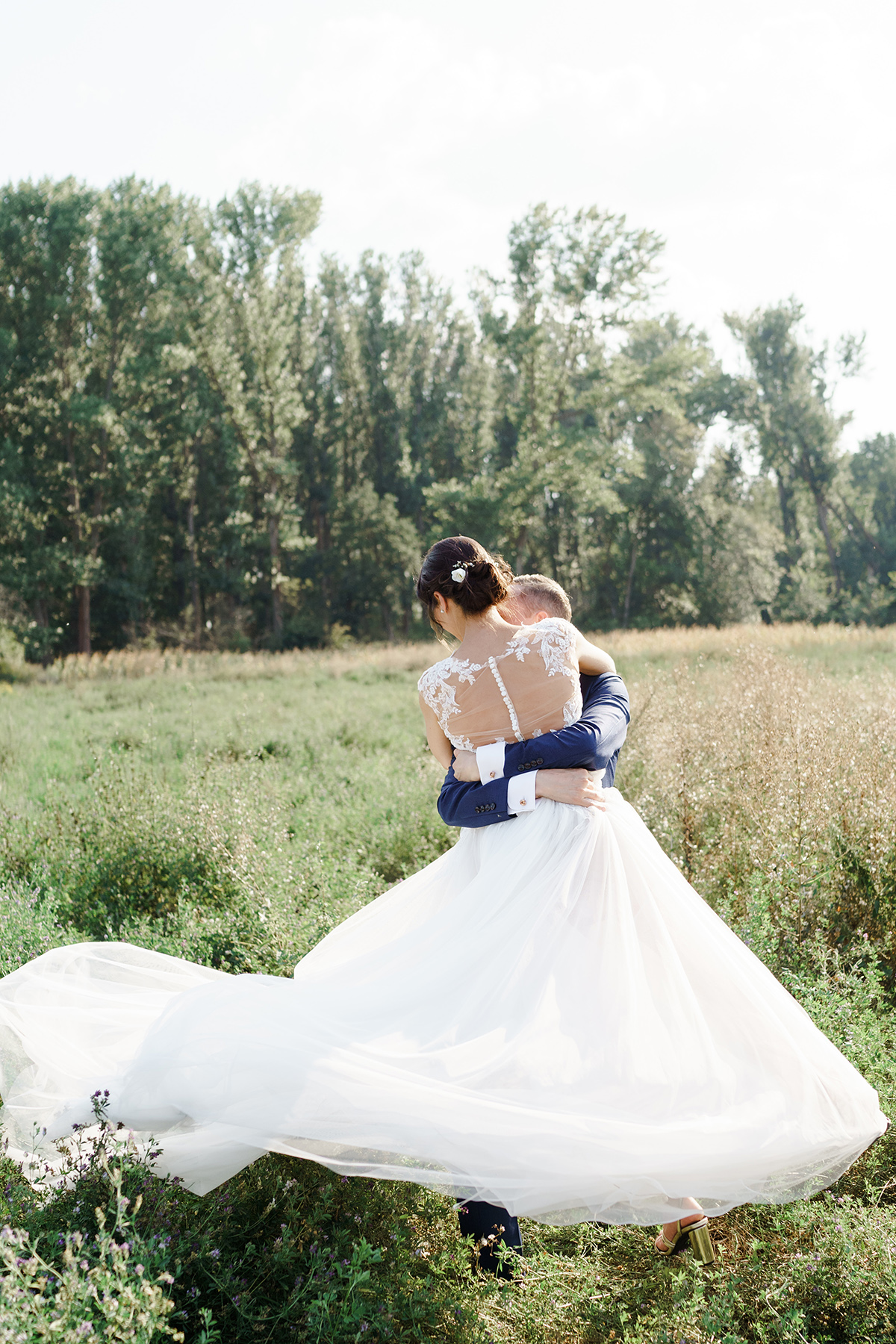 Bilder Hochzeit Idee kreativ Brautpaar trägt Braut; Brautkleid weiß lang mit Schleppe, Spitzenoberteil transparenter Rücken, schulterfrei; Brautfrisur hochgesteckt mit Haarschmuck; Bräutigam Anzug blau - Potsdam Hochzeitsfotografin im Gut Schloss Golm für Hochzeit am Wasser und im Wald © www.hochzeitslicht.de