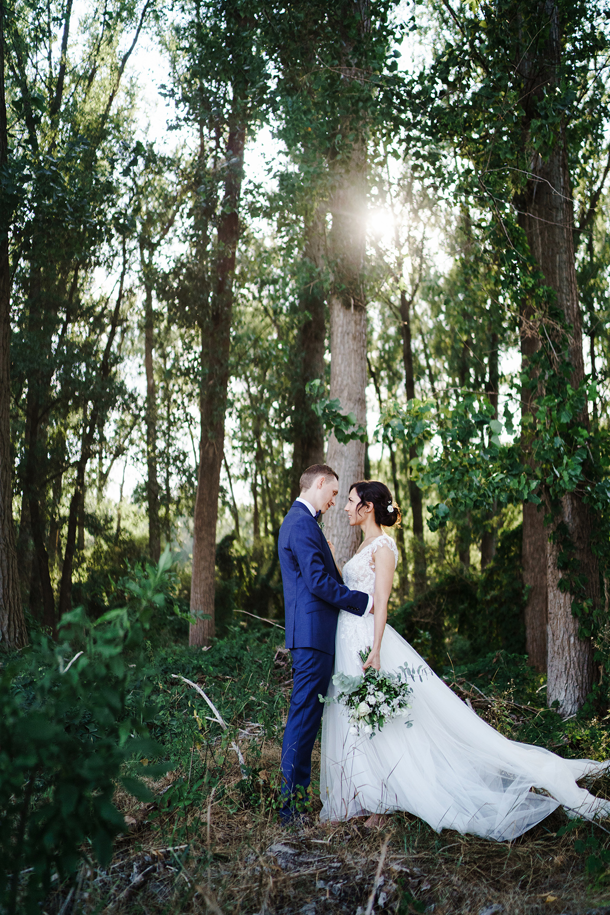 Inspiration Hochzeitsfotoshooting Wald; Hochzeitskleid weiß mit langer Schleppe, Tüllrock; Spitzenoberteil schulterfrei mit transparentem Rücken; Haare Braut hochgesteckt; Anzug Hochzeit blau; Brautstrauß schlicht elegant weiße Rosen Eukalyptus - Potsdam Hochzeitsfotografin im Gut Schloss Golm für Hochzeit am Wasser und im Wald © www.hochzeitslicht.de