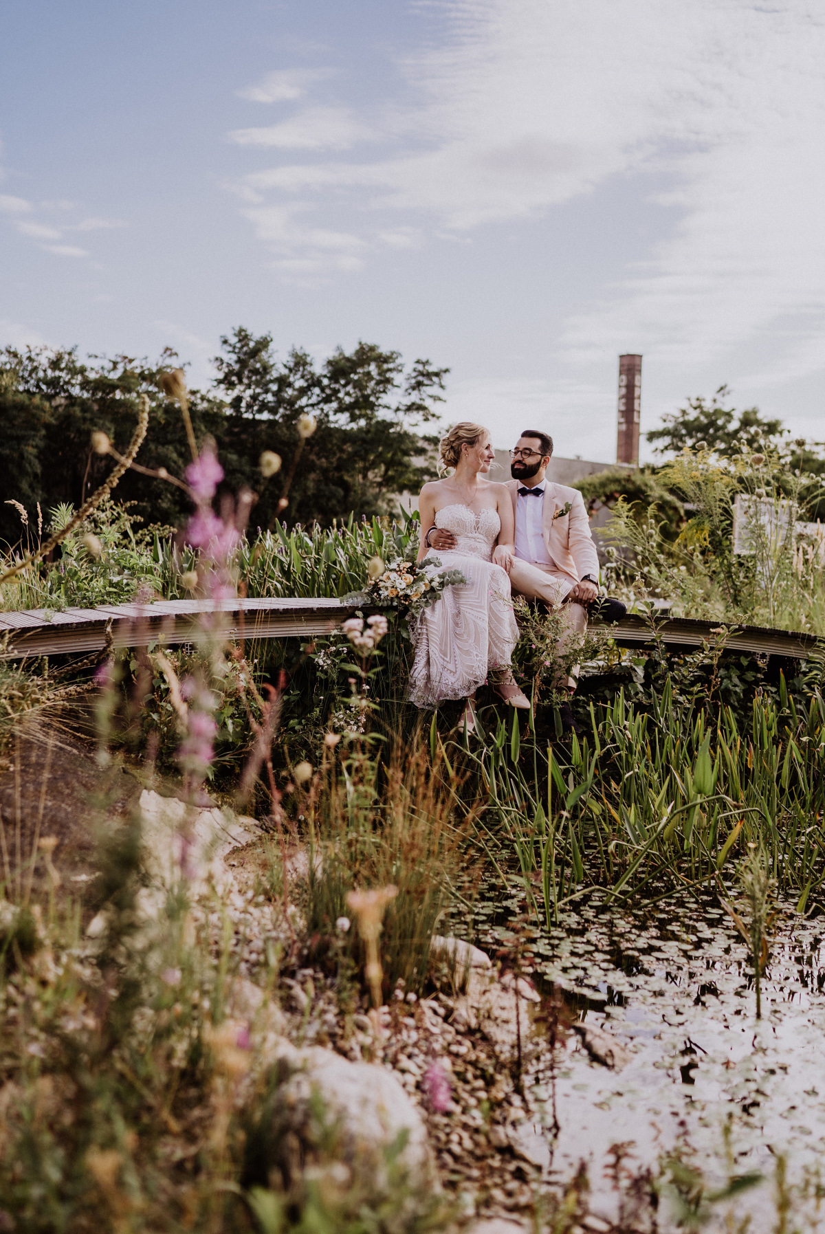 Brautpaar sitzend in Natur am Wasser im Garten Idee Fotoshooting Hochzeit im Grünen - Persische Boho-Chic Hochzeit in der Malzfabrik Berlin von Hochzeitsfotografin aus Berlin Friedrichshain © www.hochzeitslicht.de #hochzeitslicht