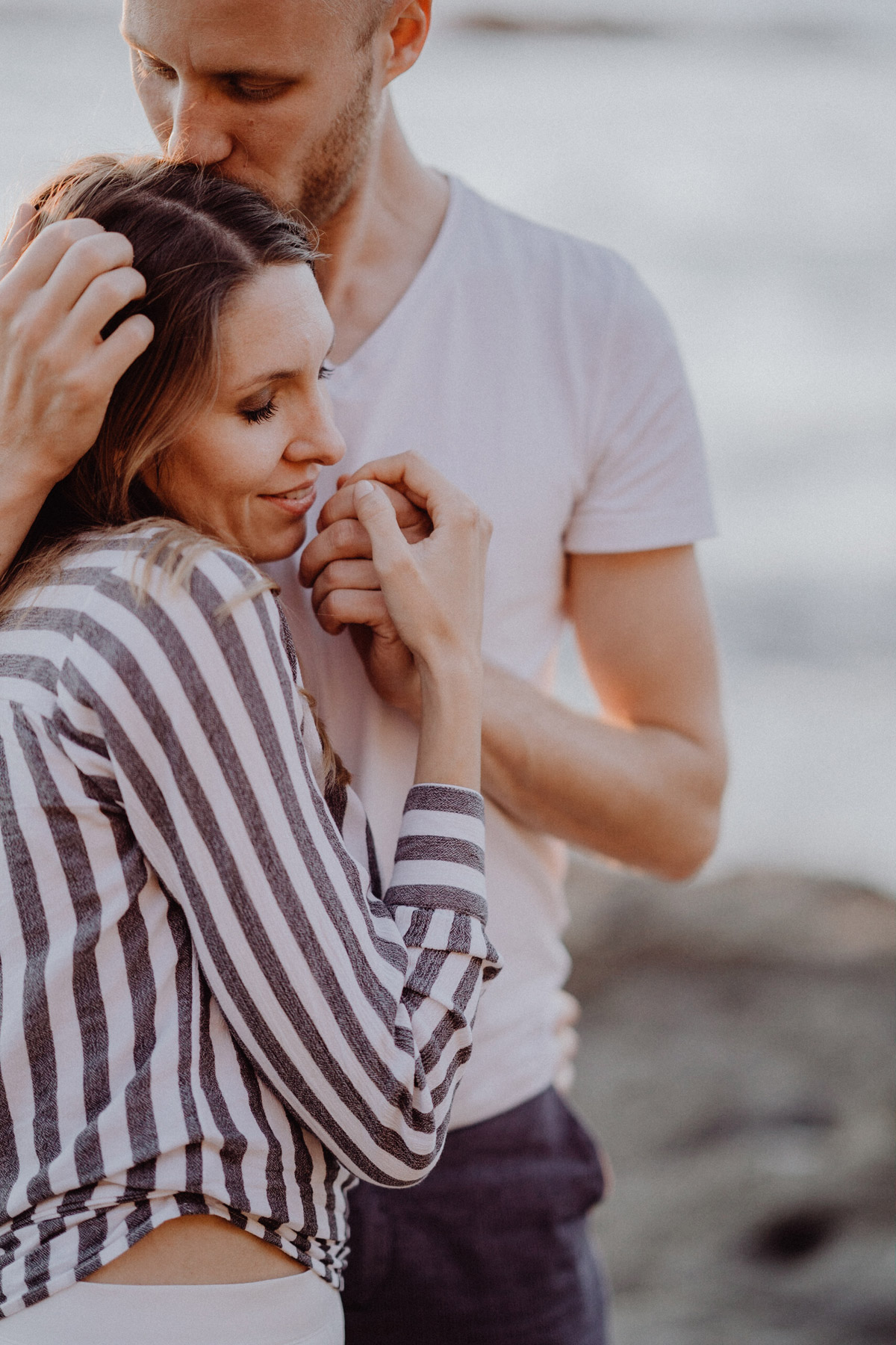 Paarfotos Fotograf aus Berlin © www.hochzeitslicht.de #hochzeitslicht Ideen für Kuscheln, innige Pose, Mann küsst Frau auf Kopf während Paarfotoshootings am Meer #kuss #paarfotos