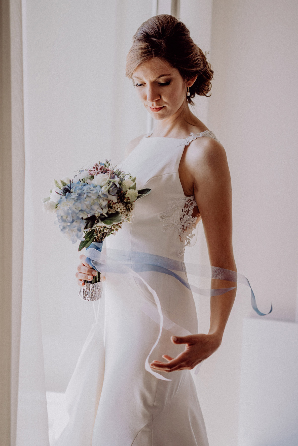 Braut bei maritimer Hochzeit mit hellblau weißen Hochzeitsblumen Brautstrauß mit Hortensien und blauen Bändern - elegantes Strandhochzeit Kleid mit Spitze im Rücken - Hochsteckfrisur Frisur Blumen Kleid Strandhochzeit Toskana Hochzeitsfotograf und Hochzeitsfilmer aus Berlin #hochzeitslicht © www.hochzeitslicht.de