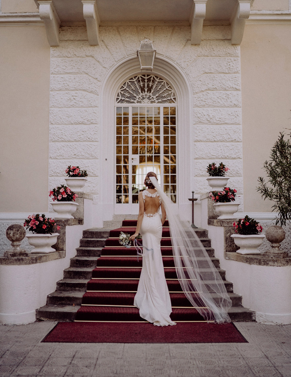 Hochzeitsfotos Hochzeitsbilder Ideen Braut von hinten vor Standesamt ausgefallen in rückenfreiem Kleid auf Treppe mit langem Schleier und Hochsteckfrisur auf maritimer Hochzeit #hochzeitslicht Toskana Hochzeitsfotos und Hochzeitsfilm © Destination-Hochzeitsfotograf www.hochzeitslicht.de