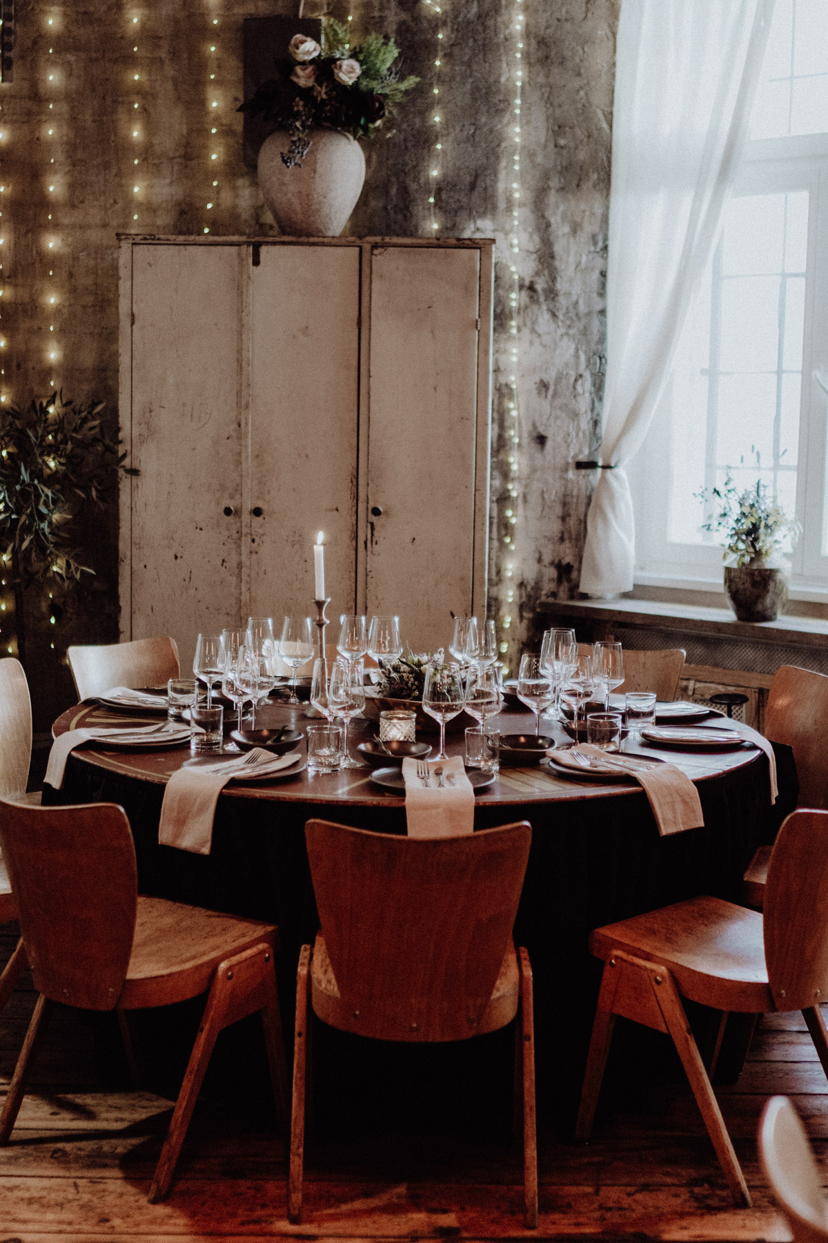 Homo Hochzeit Deko: Tischdekoration runde Tische für schwule bzw. gleichgeschlechtliche Männerhochzeit mit Frühlingsblumen in Weiß-Grün, Servietten in Beige, dunklem Geschirr und Besteck in Silber auf dunklem Holztisch, Kerze und Lichterketten zur Beleuchtung in Berlin Friedrichshain in Hochzeitslocation Alte Schmiede / Old Smithy's Dizzle von Hochzeitsfotograf © www.hochzeitslicht.de #hochzeitslicht #gleichgeschlechtlich #homo #hochzeit #gaywedding