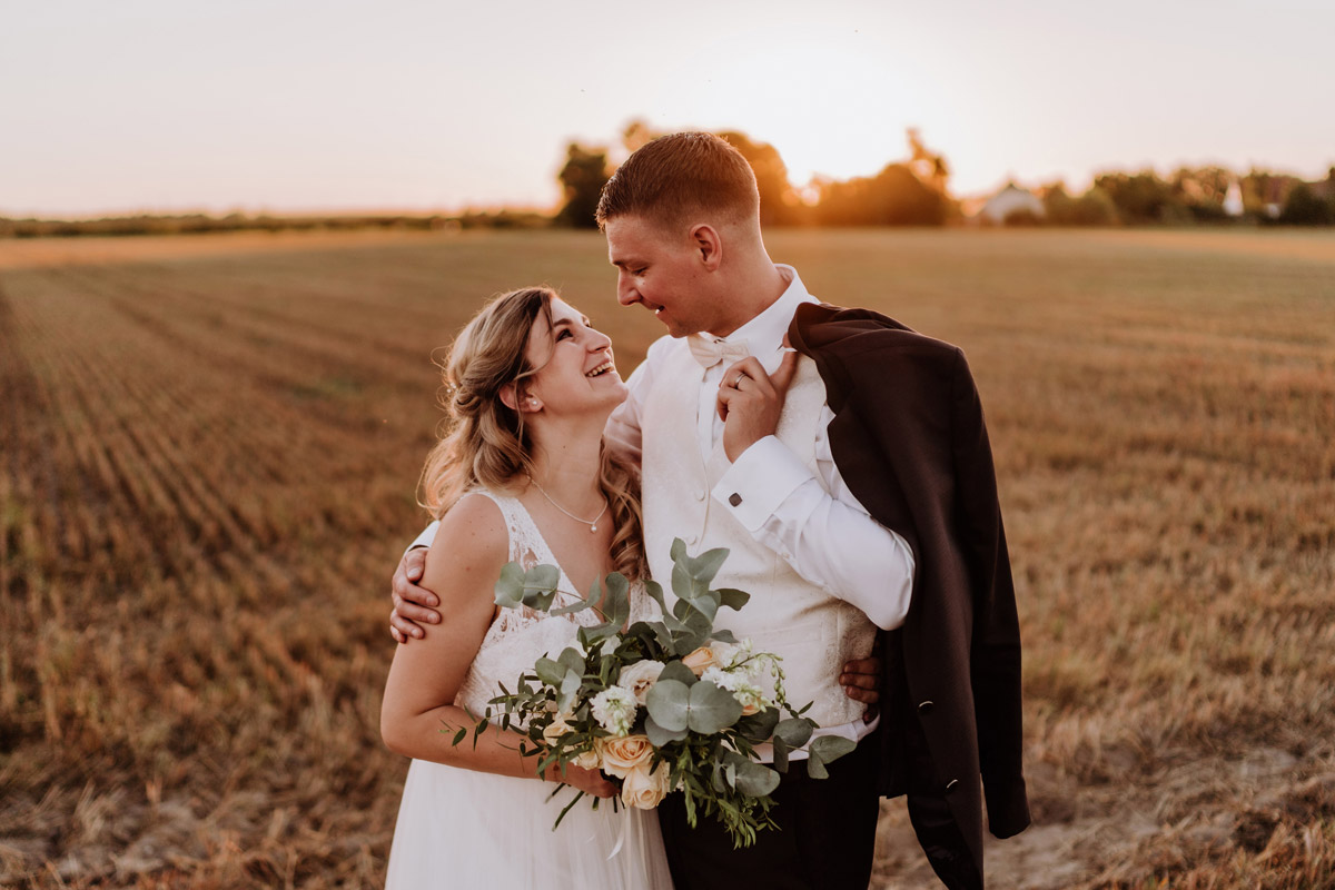 Fotoshooting Brautpaar nach standesamtlicher Hochzeit bei Sonnenuntergang auf Feld - natürliche Hochzeitsfotos Standesamt auf Schloss Kartzow von Hochzeitsfotograf Berlin © www.hochzeitslicht.de #hochzeitslicht