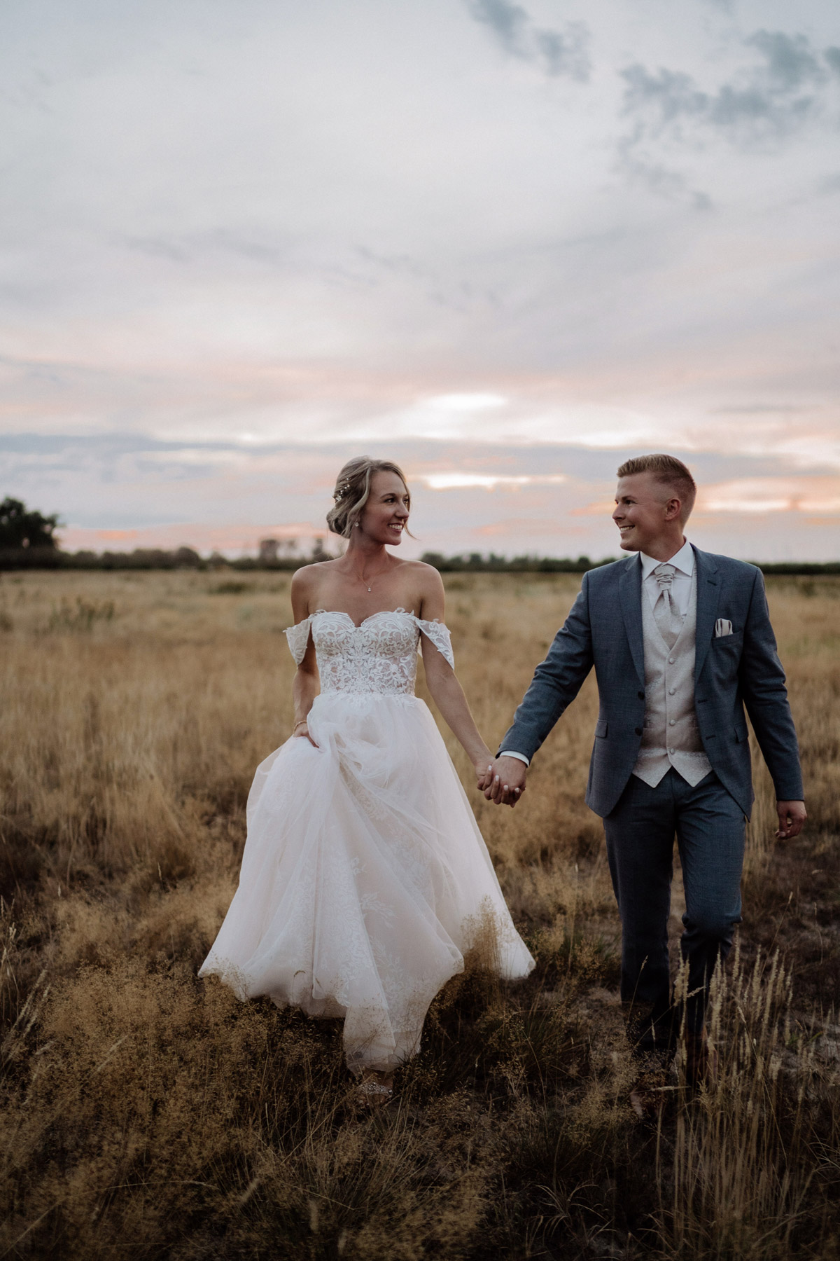 Hochzeit Shooting Idee Brautpaar nach standesamtlicher Hochzeit bei Sonnenuntergang auf Feld - natürliche Hochzeitsfotos von vintage Hochzeitsfotograf Berlin © www.hochzeitslicht.de #hochzeitslicht Tipp: für natürliche Hochzeitsbilder lacht euch im Gehen zu #hochzeit #brautpaarfoto #hochzeitsshooting #ideen