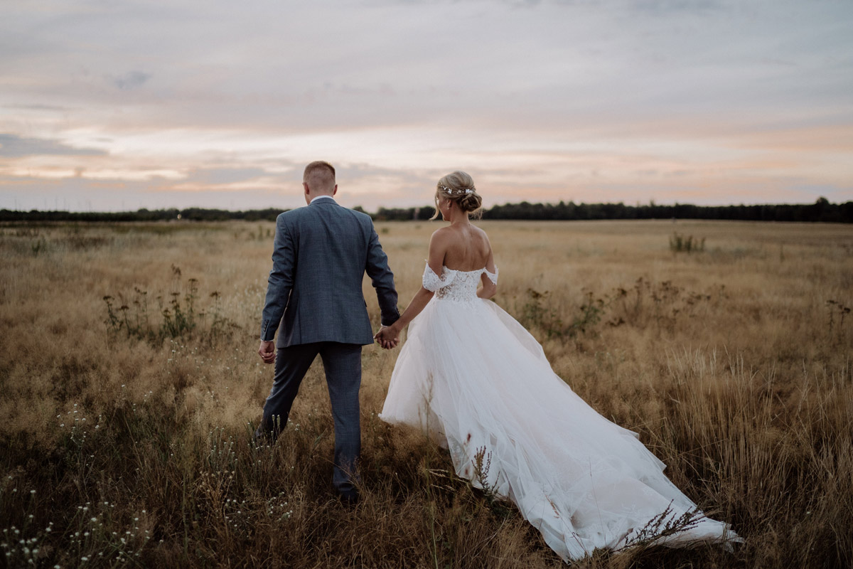 Fotoshooting Braut und Bräutigam laufen bei Sonnenuntergang auf Feld - Hochzeit Shooting Ideen von vintage Hochzeitsfotograf Berlin © www.hochzeitslicht.de #hochzeitslicht auf Schloss Kartzow