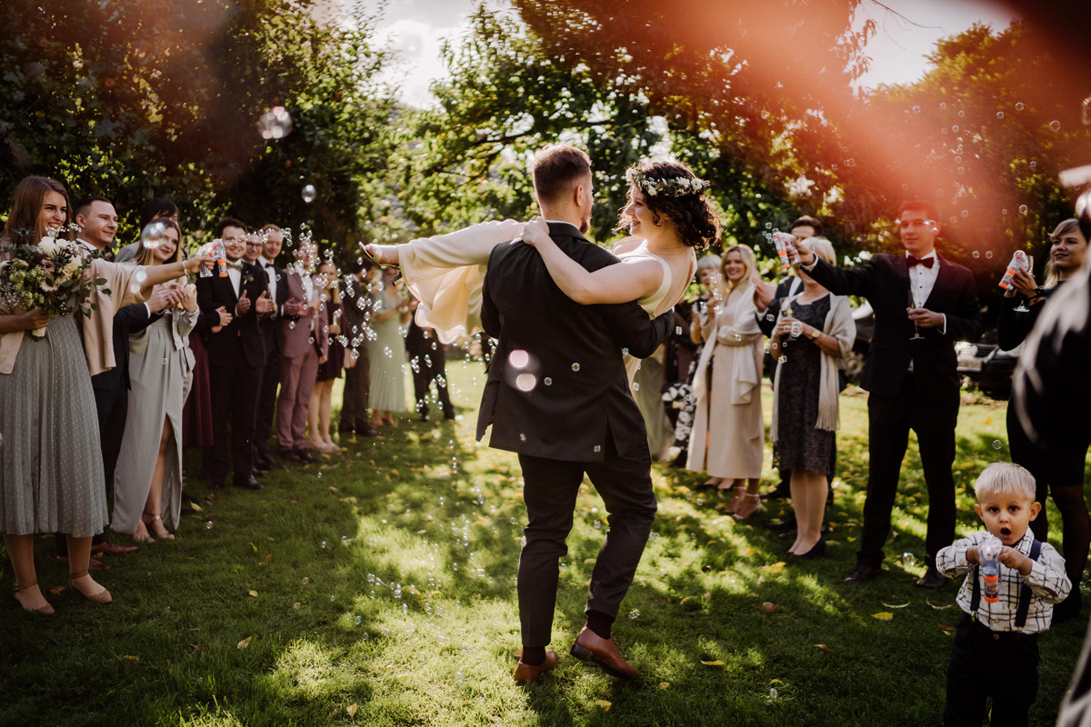 Idee Hochzeitsfoto Auszug Brautpaar Gäste Spalier Seifenblasen Bräutigam trägt Braut auf Händen - Standesamt Corona Hochzeit in Brandenburg mit Hochzeitsfilm von Hochzeitsvideograf Berlin in Bekemühle in Dannenwalde © www.hochzeitslicht.de #hochzeitslicht