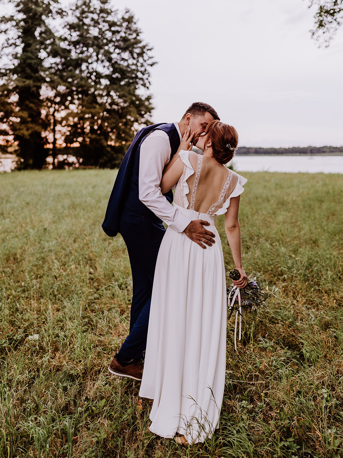 Brautpaar Fotoshooting: Hochzeitsfoto Idee von hinten - Ehepaar küsst sich in modernem vintage Brautoutfit - mehr Kavalierhaus Caputh Hochzeit Fotos aus Corona Zeit im Blog von vintage Hochzeitsfotograf Brandenburg Potsdam © www.hochzeitslicht.de #hochzeitslicht