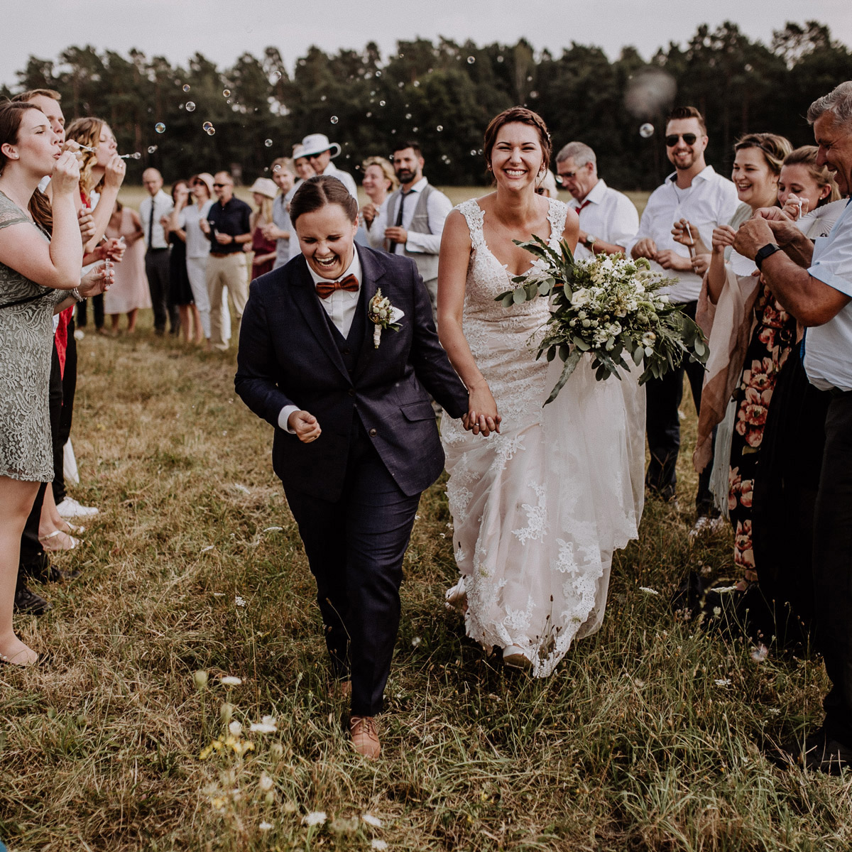 Gleichgeschlechtliche Hochzeit Frauen: zwei Bräute beim Auszug nach Trauung auf Feld in Nähe Hochzeitslocation Gut Sarnow in Brandenburg von Hochzeitsfotograf Berlin © www.hochzeitslicht.de #hochzeitslicht