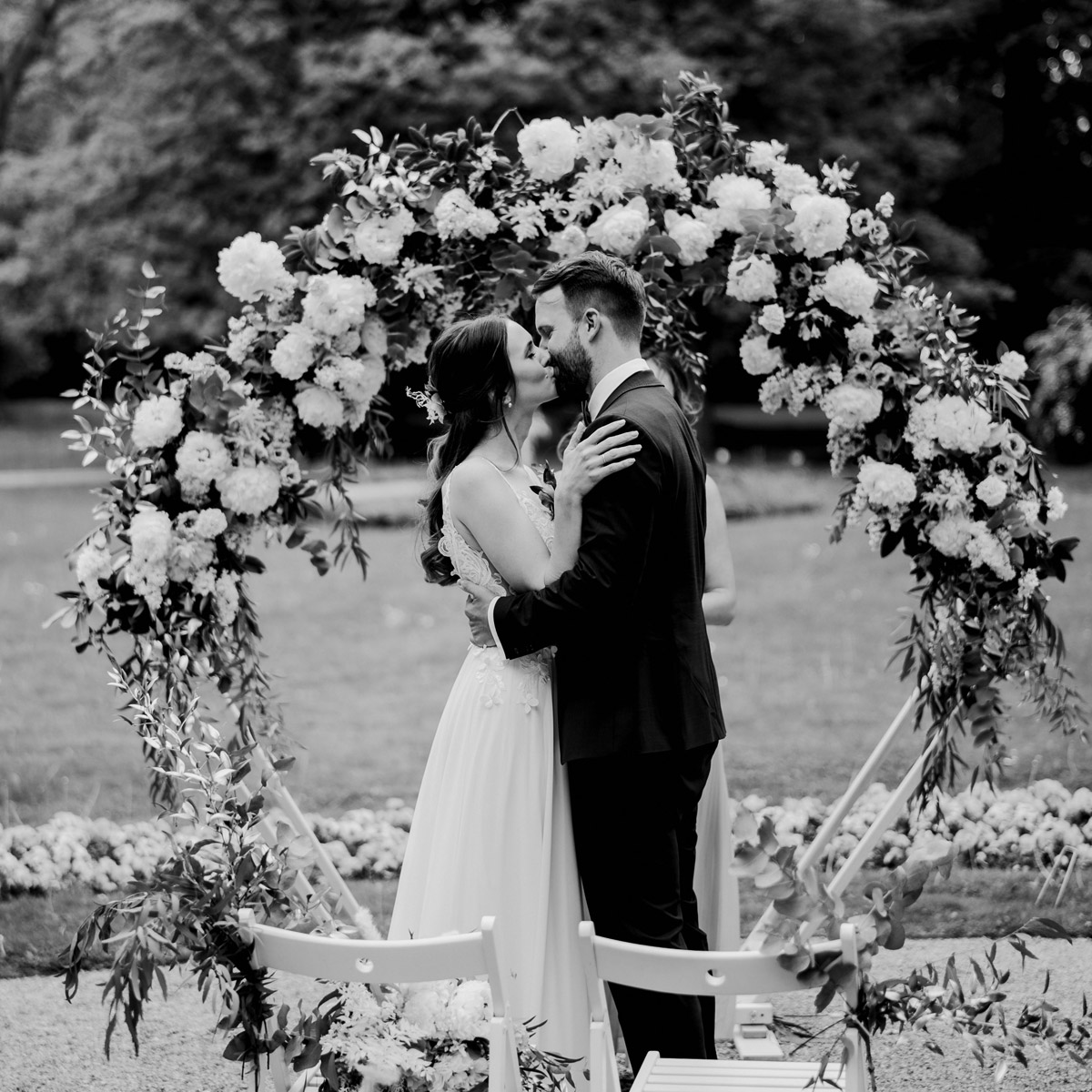 Verliebtes Ehepaar küsst sich unter Blumenbogen bei freier Trauung im Schlosspark Britz in Berlin - die Hochzeit endete im Regen - Hochzeitsreportage im Hochzeitsblog © www.hochzeitslicht.de #hochzeitslicht