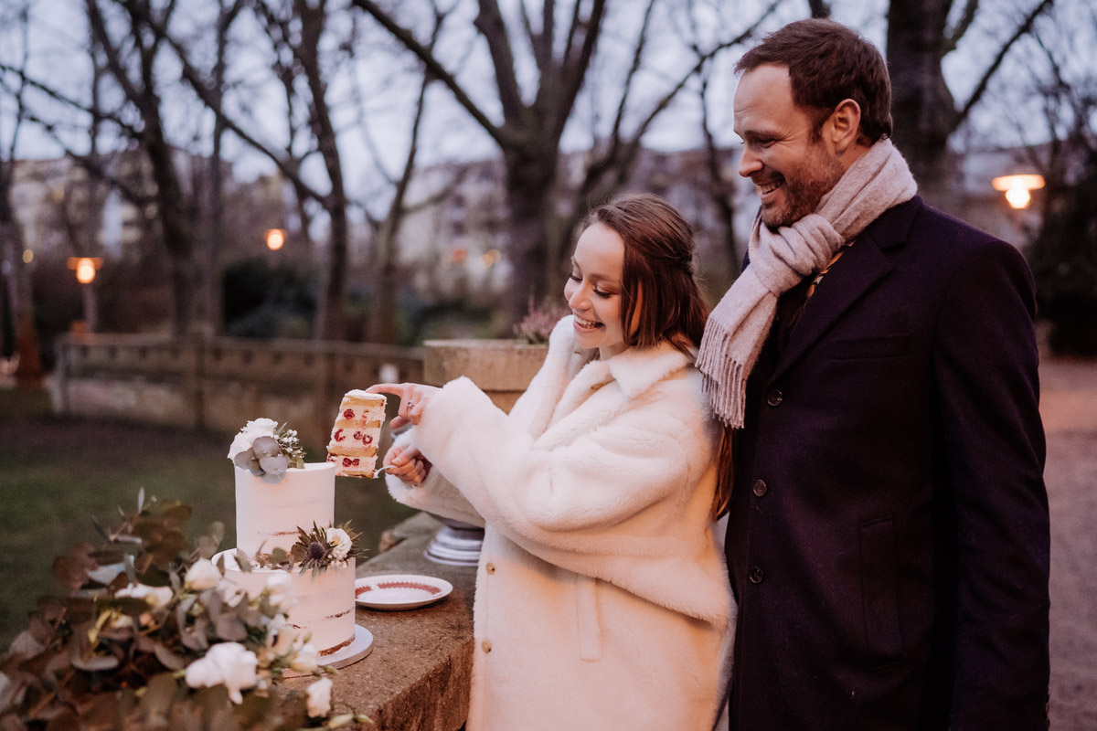 Anschneiden Hochzeitstorte draußen Coronahochzeit - Winterhochzeit im Standesamt Rathaus Schöneberg, Hotel Adlon Kempinski und Restaurant Berlin von Fine Art Hochzeitsfotograf Berlin © www.hochzeitslicht.de #hochzeitslicht