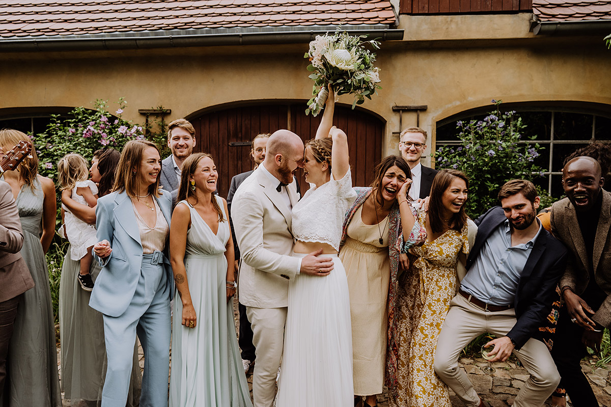 Idee lustiges Gruppenfoto Brautpaar mit Gästen auf Gut Wendgräben Hochzeit in Boho Scheune