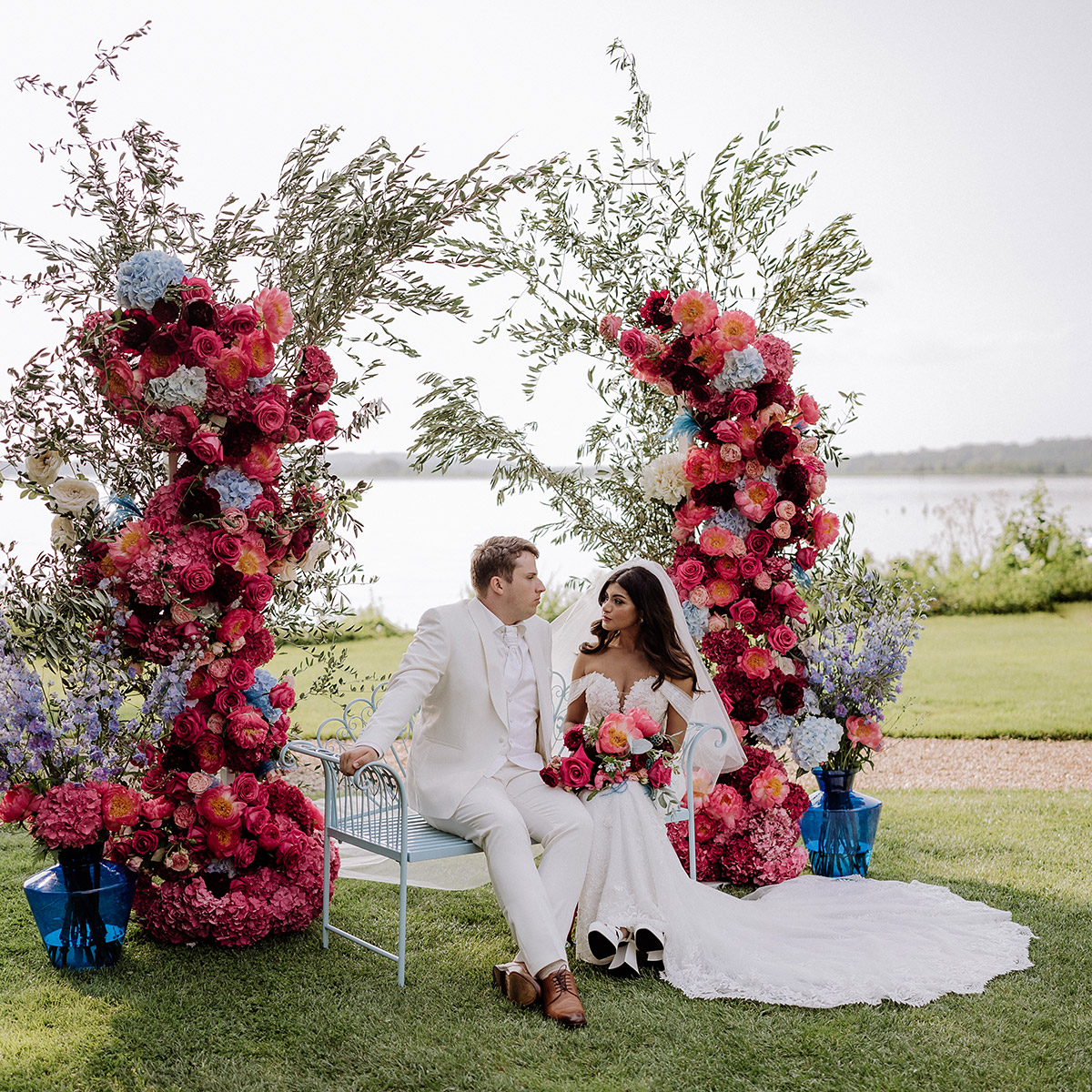 Traubogen aus zwei Blumensäulen in hellblau und pink: Idee für Hochzeitsfotografie - Hochzeitspaar sitzt auf Bank und unterhält sich - Mehr Gut Schloss Golm und Garten Hochzeitsbilder im Blog von © www.hochzeitslicht.de #hochzeitslicht