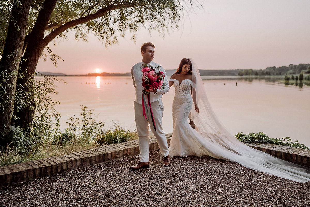 Hochzeitsfotos Hochzeitspaar am See Braut mit langem Schleier - Hochzeitsfotografin aus Berlin auf eleganter Gartenhochzeit in Hochzeitslocation Potsdam am Wasser im Gut Schloss Golm während Corona Pandemie © www.hochzeitslicht.de #hochzeitslicht