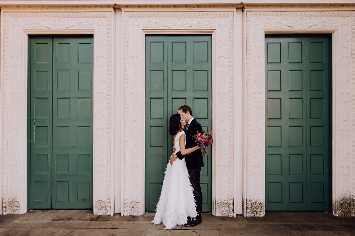 Hochzeitsfotograf Potsdam hält sich küssendes Paar vor Wand fest