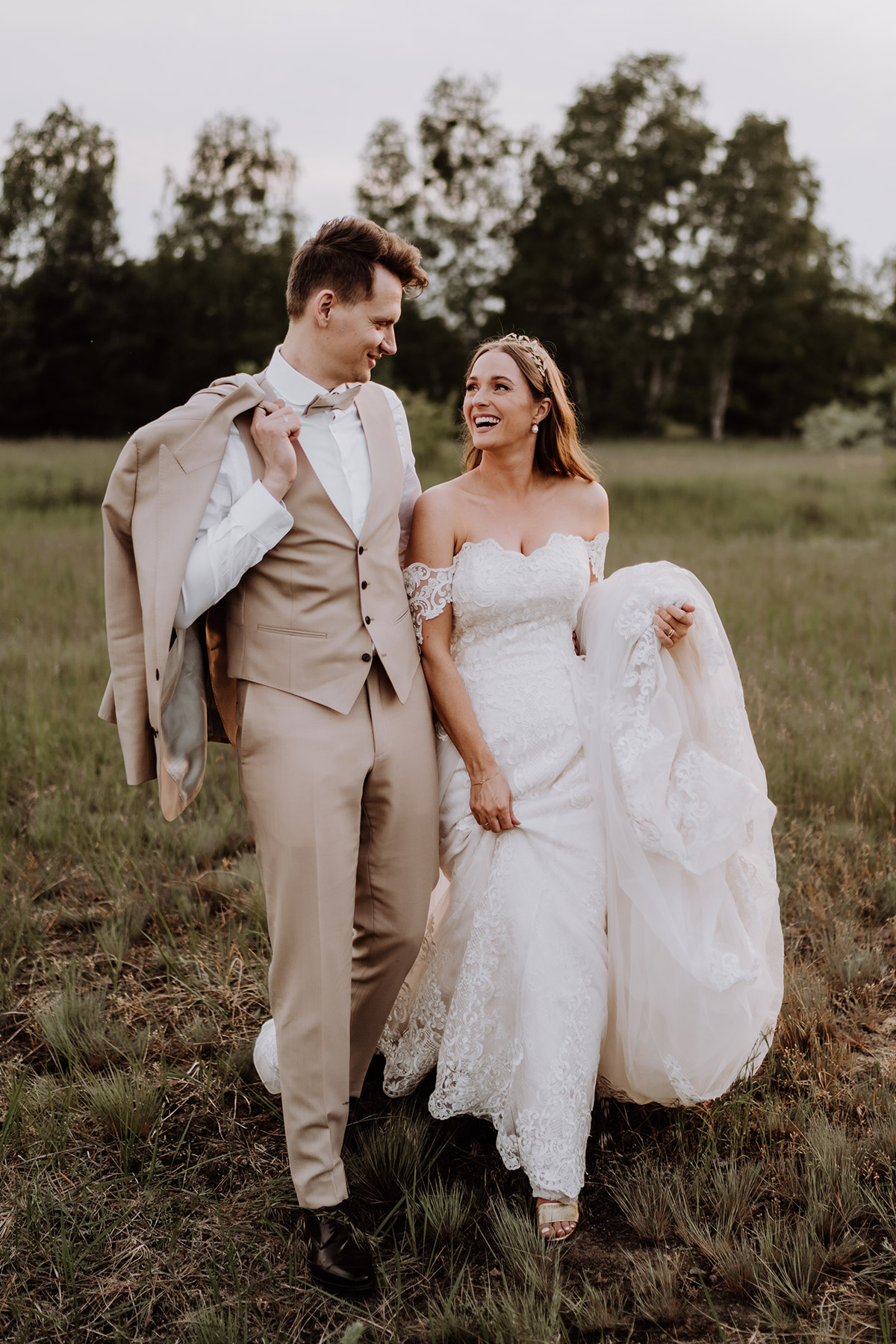 Boho Glam Hochzeits Outfit: Der Bräutigam trägt einen hellen Anzug in Beige mit Weste. Das Brautkleid mit Schleppe und Ärmeln aus Spitze war perfekt für die Kirche und die Brautpaar Fotoshooting Ideen auf einem Feld in der Natur. KLICKE DEN LINK ZUM BLOG. © www.hochzeitslicht.de #hochzeitslicht