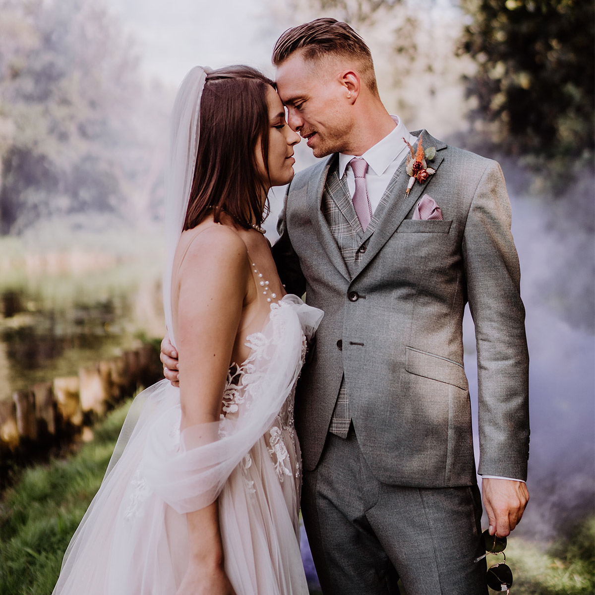 Hochzeitsfoto mit Rauchfackel im Hintergrund: Eine klassische Pose im Hochzeitsfotoshooting ist wenn das Paar Stirn an Stirn geht. Dabei war die Boho Hochzeit in Brandenburg alles andere als klassisch. Sieh dir den Blog an! © www.hochzeitslicht.de #hochzeitslicht