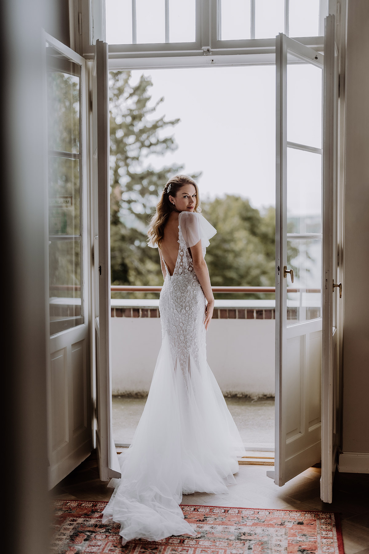 Braut am Fenster der Villa Blumenfisch Berlin: Bridal Fashion Fotos sollte die #hochzeitslicht Hochzeitsfotografin erstellen. Im Standesamt Hochzeitskleid mit abnehmbaren Ärmeln und tiefem Rückenausschnitt. LIES IM BLOG WAS IM SHOOTING ZU BEACHTEN IST. © www.hochzeitslicht.de