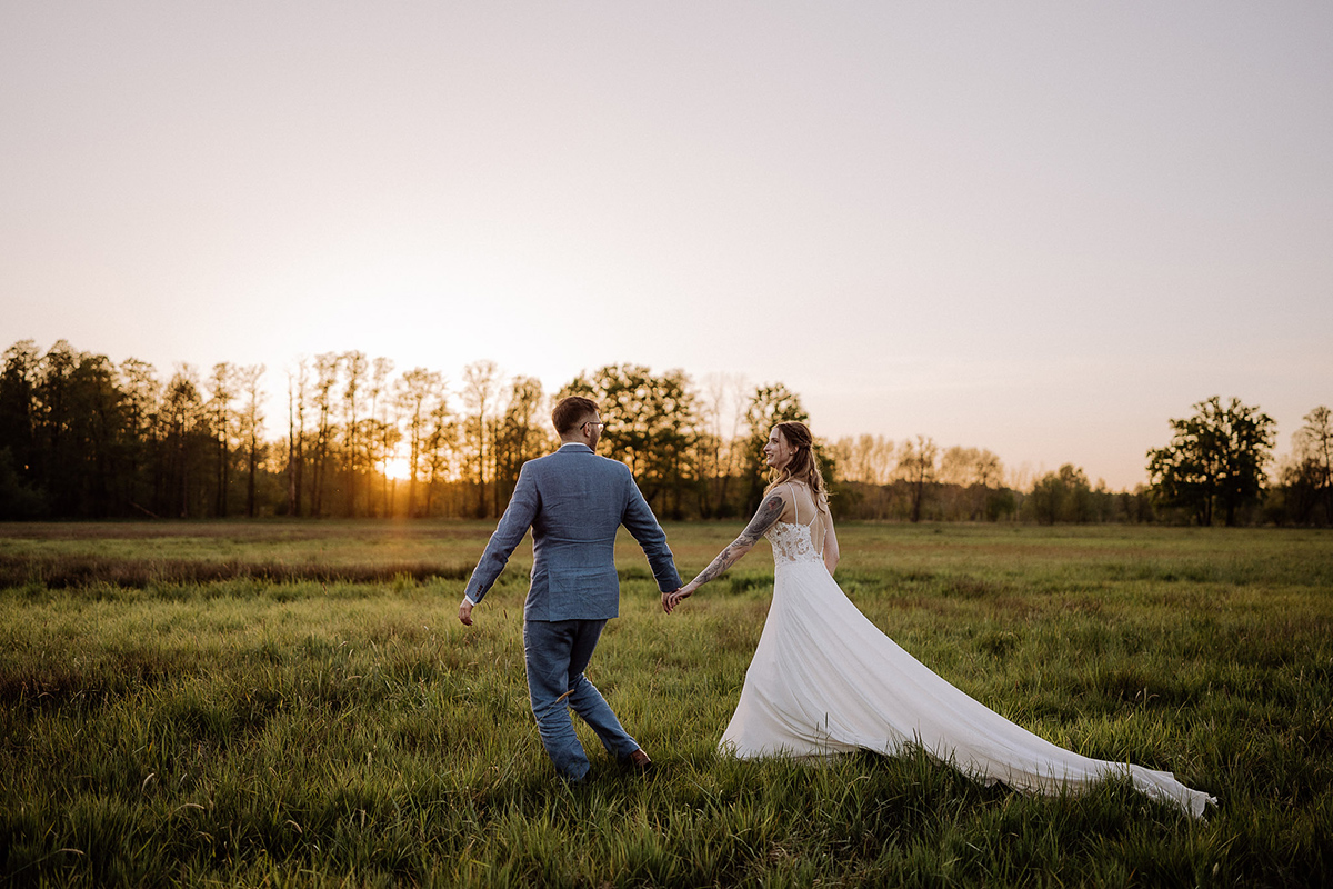 Standesamt Hochzeitsfotografin hält im Spreewald im Sonnenuntergang Fotoshooting das Paar auf Wiese im Gehen fest