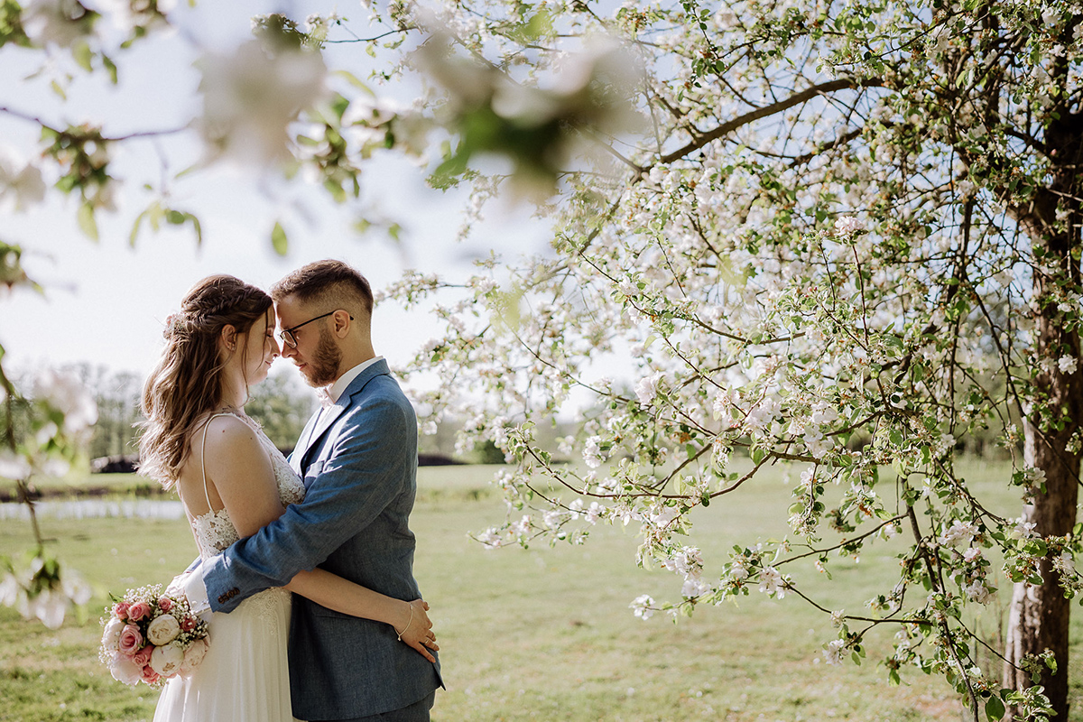 Standesamt Hochzeitsfotografin zeigt im Spreewald ihr Hochzeitspaar in natürlichen Posen unter Kirschblüten